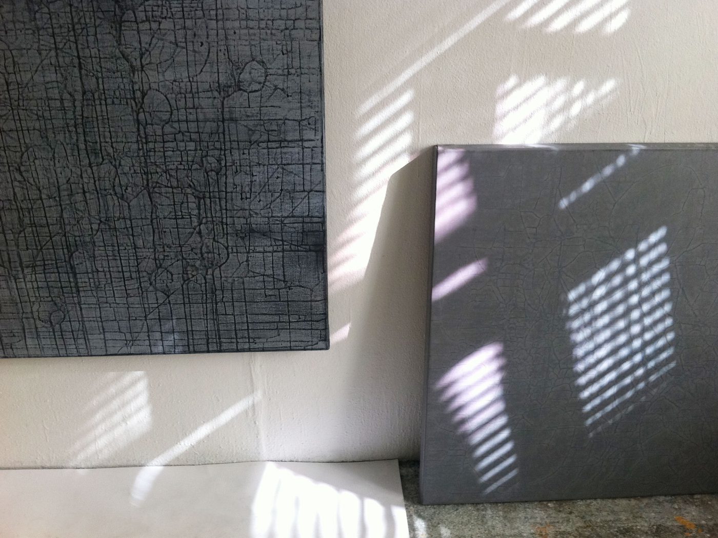 Szene im Atelier: Schattenwirkung der Fensterjalousien auf zwei Gemälden